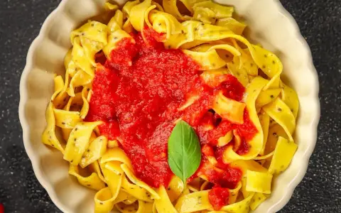 Pyszne linguine z sosem pomidorowym i listkiem bazylii. Makaron wygląda jak spaghetti, ale jest szerszy.