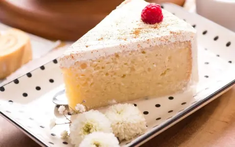 Pyszny kawałek ciasta Tres Leches, udekorowany maliną i cynamonem, czeka na spróbowanie. Idealny przepis na deser.