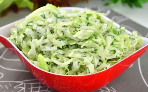 Pyszna surówka z białej kapusty jak w restauracji, z dodatkiem świeżego koperku i szczypiorku, w czerwonej misce.