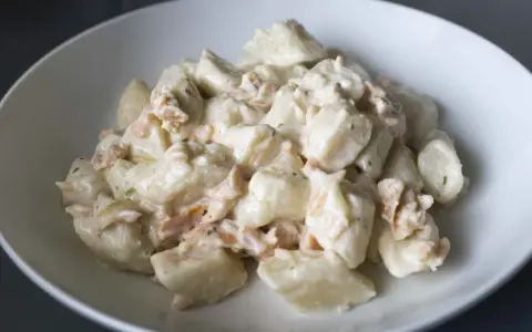 Gnocchi ziemniaczane kontra gnocchi z ricotty w kremowym sosie z łososiem. Pyszne danie w białej misce.