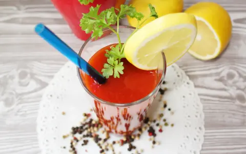 Orzeźwiający drink z sokiem pomidorowym, ozdobiony plasterkiem cytryny i natką pietruszki, gotowy do wypicia.