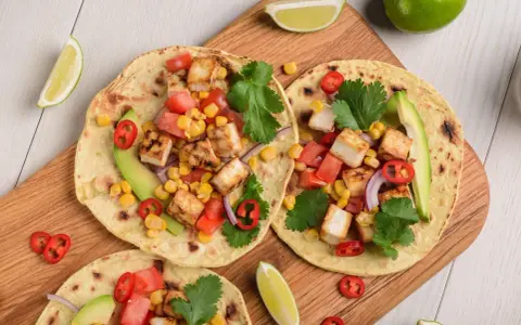 Zdrowy obiad dietetyczny: tortille z grillowanym tofu, kukurydzą, pomidorami, awokado i kolendrą.