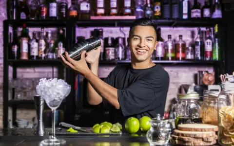 Uśmiechnięty barman miesza drinka. Chcesz wiedzieć, jak zostać barmanem kobietą? Zacznij od nauki sztuki miksowania!