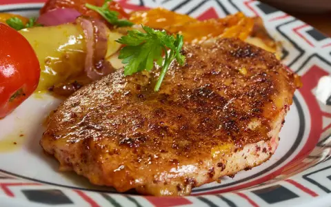 Apetyczny kotlet schabowy lub z piersi kurczaka, podany z pieczonymi warzywami i pomidorem.