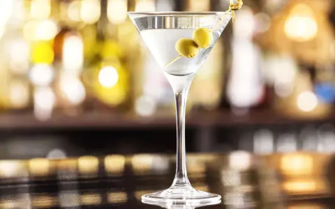 Elegancki gin z wermutem, ozdobiony dwiema oliwkami, czeka na Ciebie przy barze.