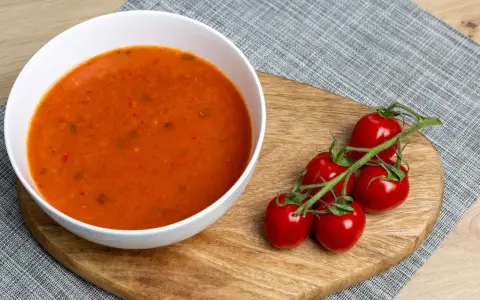 Aksamitna zupa pomidorowa z ryżem czy z makaronem? Na desce leżą świeże pomidorki koktajlowe, idealne do tej klasycznej potrawy.