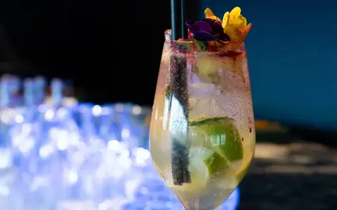 Orzeźwiający drink prosecco sprite z limonką i kwiatową dekoracją, idealny na letnie wieczory.