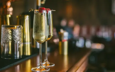 Dwa kieliszki musującego drinka z maliną na wierzchu. Idealne na domowe przyjęcie, inspiracja do drinki przepisy domowe.