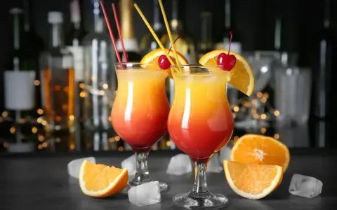 Dwa drinki ze spritem, ozdobione pomarańczą i wiśnią, na tle baru. Idealne na letnie wieczory.