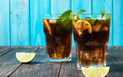 Dwa orzeźwiające drinki z rumem, lodem, limonką i miętą na drewnianym blacie. Idealny dobry drink z rumem na upalne dni.