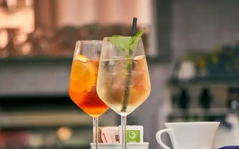 Dwa orzeźwiające drinki: pomarańczowy Aperol Spritz i zielony Hugo, gotowe do degustacji.