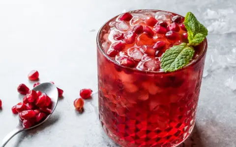 Orzeźwiający drink z grenadyną i rumem, ozdobiony świeżymi pestkami granatu i miętą. Idealny na letnie wieczory.