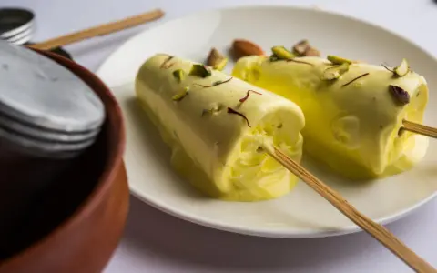Dwa pyszne kulfi na patyku, posypane pistacjami i szafranem. Idealne na upalne dni, gdy szukasz prostego kulfi przepis.