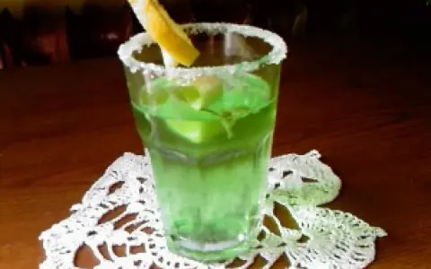 Orzeźwiający drink z likierem miętowym, lodem i plasterkiem cytryny, ozdobiony cukrowym rantem.