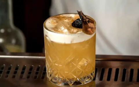 Elegancki Whisky Sour i Amaretto Sour z pianką i dekoracją na barze.