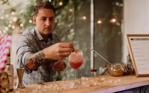 Barman z tatuażem na ręce przygotowuje drinka na 18. urodziny. Zastanawiasz się, ile kosztuje barman na 18?