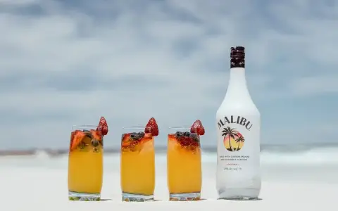 Letnie drinki z malibu na plaży, ozdobione truskawkami i borówkami. Idealne na upalne dni.