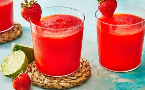 Orzeźwiający drink z truskawkami, ozdobiony świeżymi owocami i limonką, idealny na upalne dni.