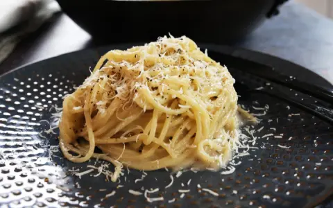 Pyszne spaghetti Cacio e Pepe, posypane startym parmezanem i świeżo mielonym pieprzem. Idealne na szybki obiad.