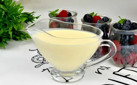 Krem custard i krem budyniowy w sosjerce, obok słoiczków z jagodami i malinami. Idealny deser na lato.