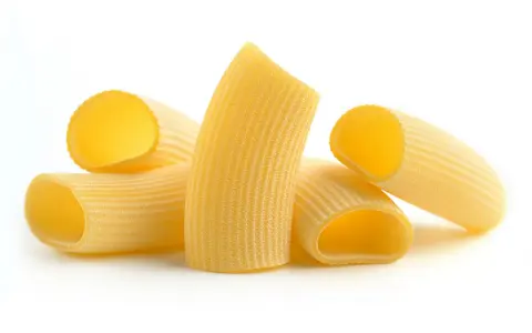 Kilka kawałków makaronu rigatoni, z charakterystycznymi rowkami, gotowych do sosu.