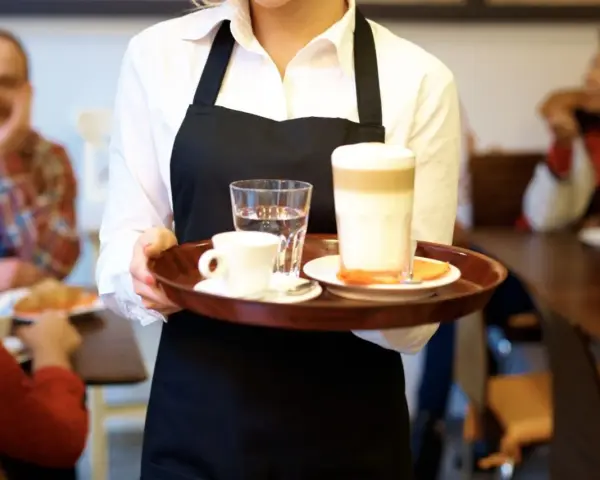 Kelnerka niesie tacę z kawą i wodą. Zastanawiasz się, ile zarabia barman w Sopocie?