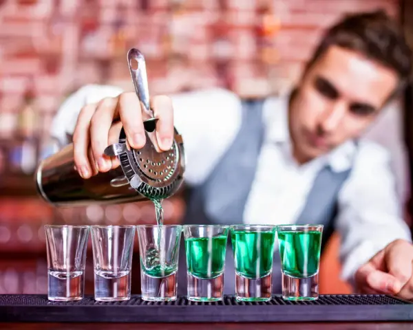 Barman nalewa zielony shot. Chcesz wiedzieć, jak zostać barmanem? To pierwszy krok do mistrzostwa!