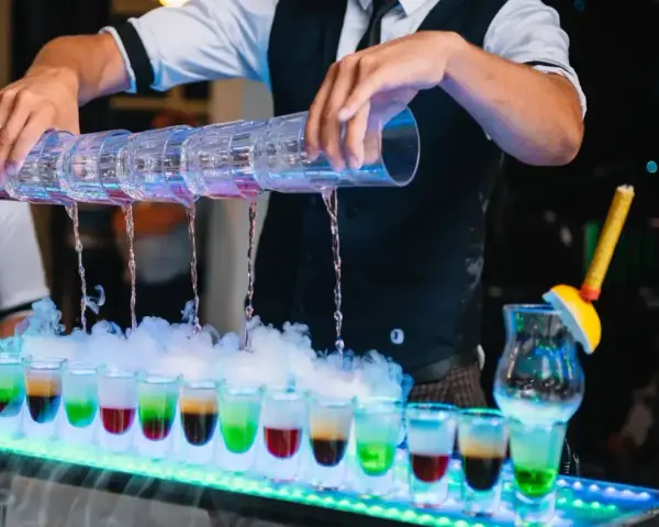 Barman nalewa kolorowe shoty na weselu. Zastanawiasz się, ile bierze barman na weselu za taką atrakcję?