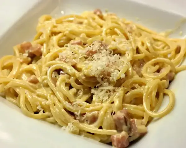 Pyszne spaghetti carbonara ze śmietaną, posypane parmezanem. Idealne na szybki obiad.