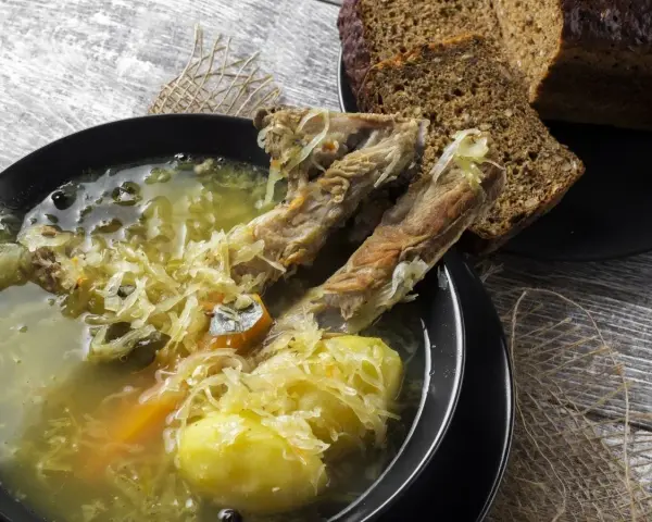 Kapuśniak ze świeżej kapusty czy kwaśnica? Aromatyczna zupa z żeberkami, ziemniakami i kiszoną kapustą, podana z ciemnym chlebem.