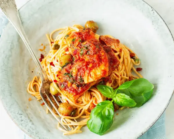 Spaghetti Puttanesca przepis: makaron z rybą w sosie pomidorowym, oliwkami, kaparami i bazylią. Pyszne danie gotowe do podania.