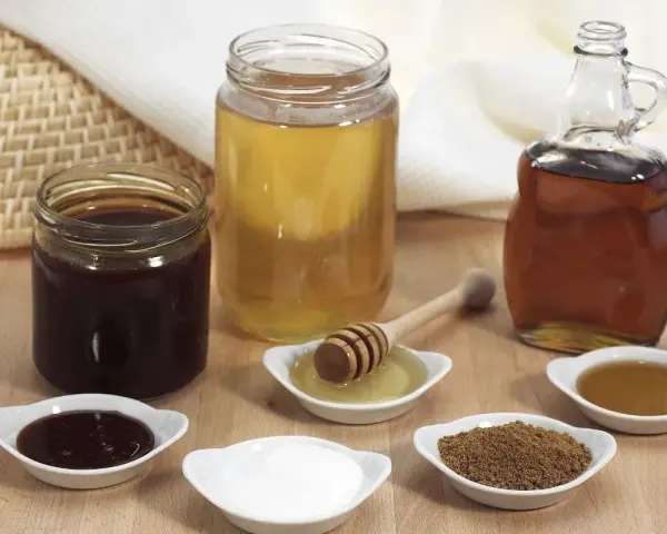 Domowy syrop cukrowy i kupny syrop barmański obok miodu i cukru.