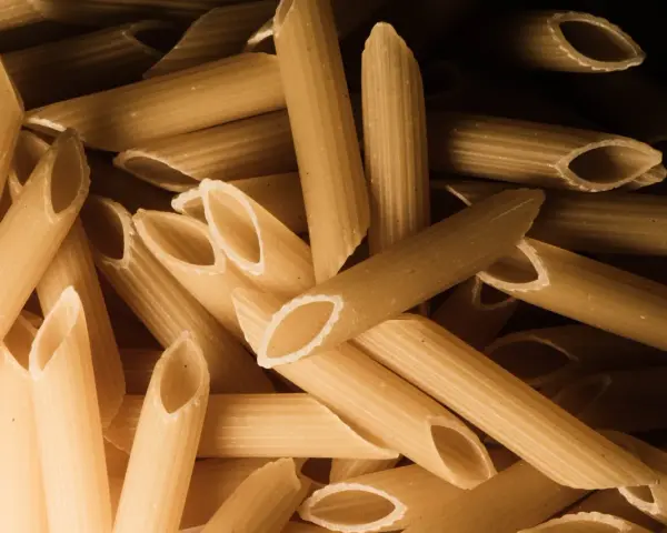 Stos makaronu penne, czy to orkiszowy czy żytni, czeka na gotowanie.
