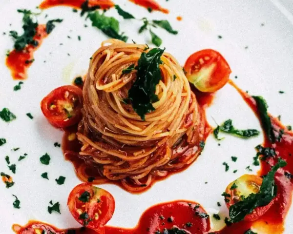 Eleganckie spaghetti bez mięsa, podane z sosem pomidorowym, świeżymi pomidorkami koktajlowymi i posypane ziołami.