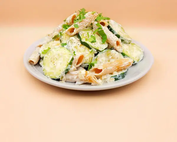 Makaron z cukinii przepis: penne w kremowym sosie z plasterkami cukinii, posypane natką pietruszki i pieprzem.