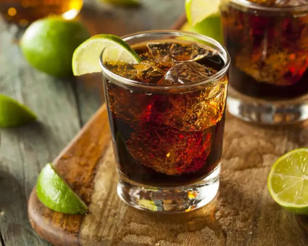 Orzeźwiający drink z rumem Bacardi, lodem i limonką na drewnianej desce.