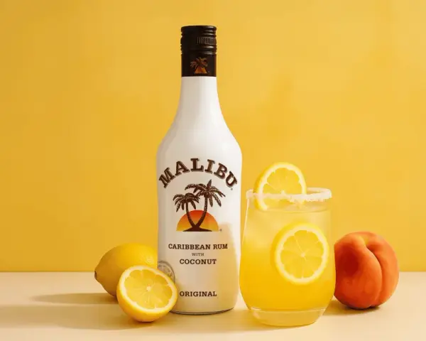 Orzeźwiający drink z malibu przepis: kokosowy rum, cytryny i brzoskwinia na żółtym tle. Idealny na lato!