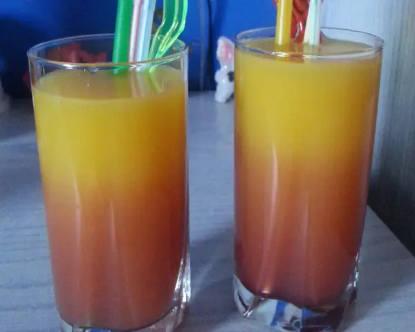 Dwa orzeźwiające drinki z sokiem malinowym, tworzące piękny gradient od czerwieni do żółci, gotowe do degustacji.