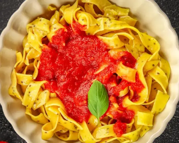 Pyszne linguine z sosem pomidorowym i listkiem bazylii. Makaron wygląda jak spaghetti, ale jest szerszy.