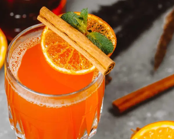 Orzeźwiający aperol z wódką, ozdobiony plasterkiem pomarańczy, listkami mięty i laską cynamonu. Idealny na letnie wieczory.
