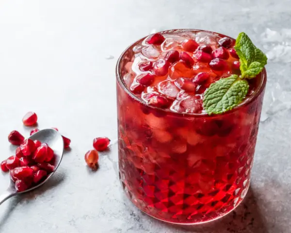 Orzeźwiający drink z grenadyną i rumem, ozdobiony świeżymi pestkami granatu i miętą. Idealny na letnie wieczory.