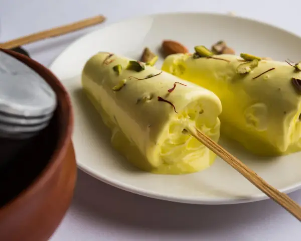 Dwa pyszne kulfi na patyku, posypane pistacjami i szafranem. Idealne na upalne dni, gdy szukasz prostego kulfi przepis.
