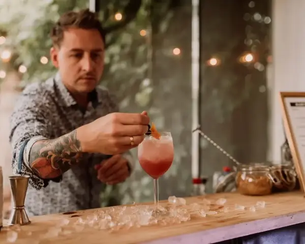 Barman z tatuażem na ręce przygotowuje drinka na 18. urodziny. Zastanawiasz się, ile kosztuje barman na 18?