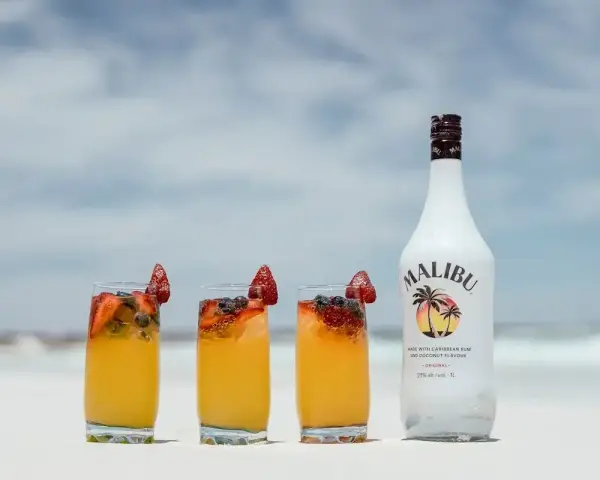 Letnie drinki z malibu na plaży, ozdobione truskawkami i borówkami. Idealne na upalne dni.