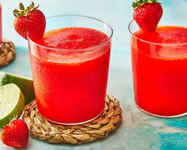 Orzeźwiający drink z truskawkami, ozdobiony świeżymi owocami i limonką, idealny na upalne dni.