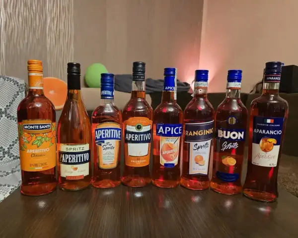 Pimm’s No. 1 kontra Aperol Spritz: rząd butelek włoskich aperitifów, głównie pomarańczowych, gotowych na imprezę.