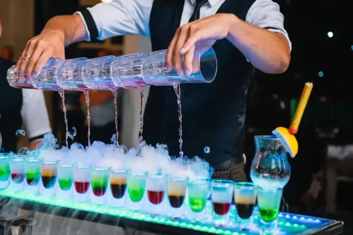 Barman nalewa kolorowe shoty na weselu. Zastanawiasz się, ile bierze barman na weselu za taką atrakcję?