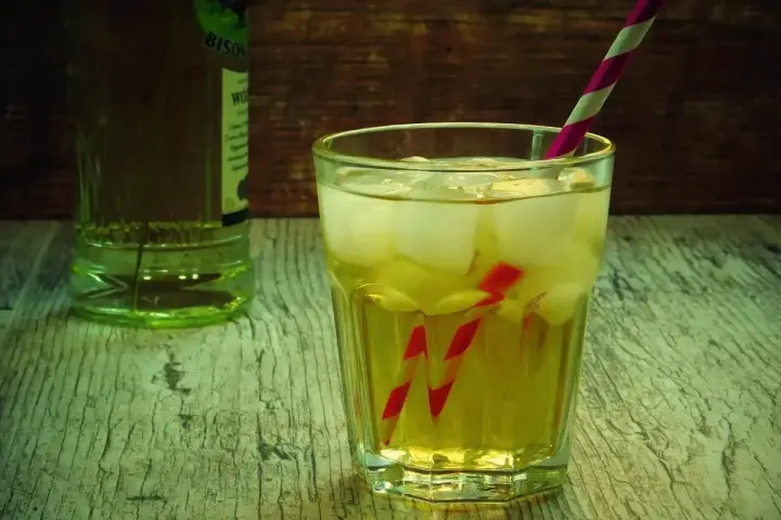 Orzeźwiający drink z lodem i słomką, idealny do przygotowania według przepisu na French Martini. Obok butelka alkoholu.