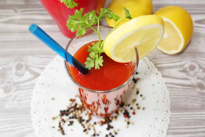 Orzeźwiający drink z sokiem pomidorowym, ozdobiony plasterkiem cytryny i natką pietruszki, gotowy do wypicia.