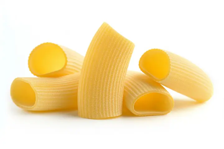 Kilka kawałków makaronu rigatoni, z charakterystycznymi rowkami, gotowych do sosu.